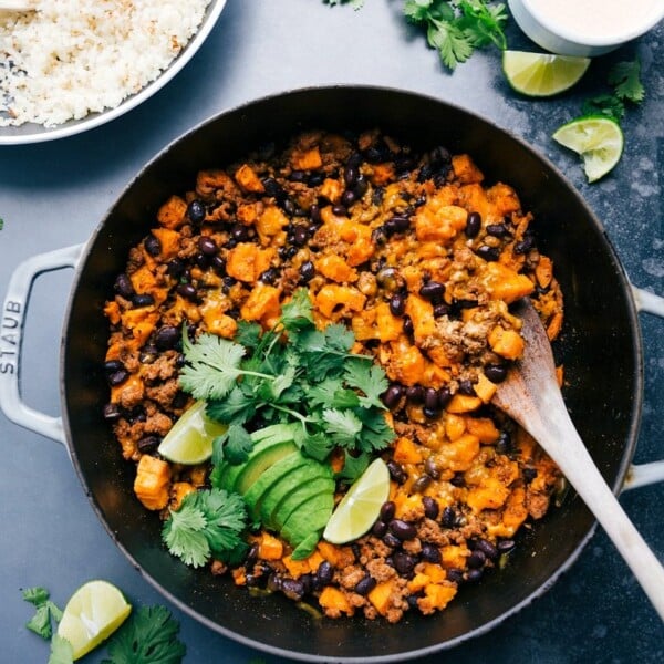 A pan full of ground turkey sweet potato skillet, accompanied by a bowl of rice, presenting a hearty and savory meal.