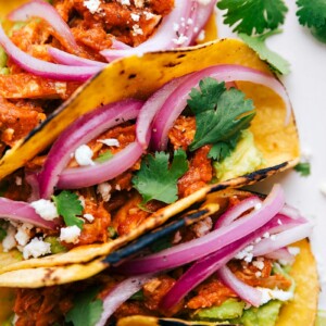 A fully assembled and stuffed meal, filled with pickled red onions, guacamole, and cilantro.