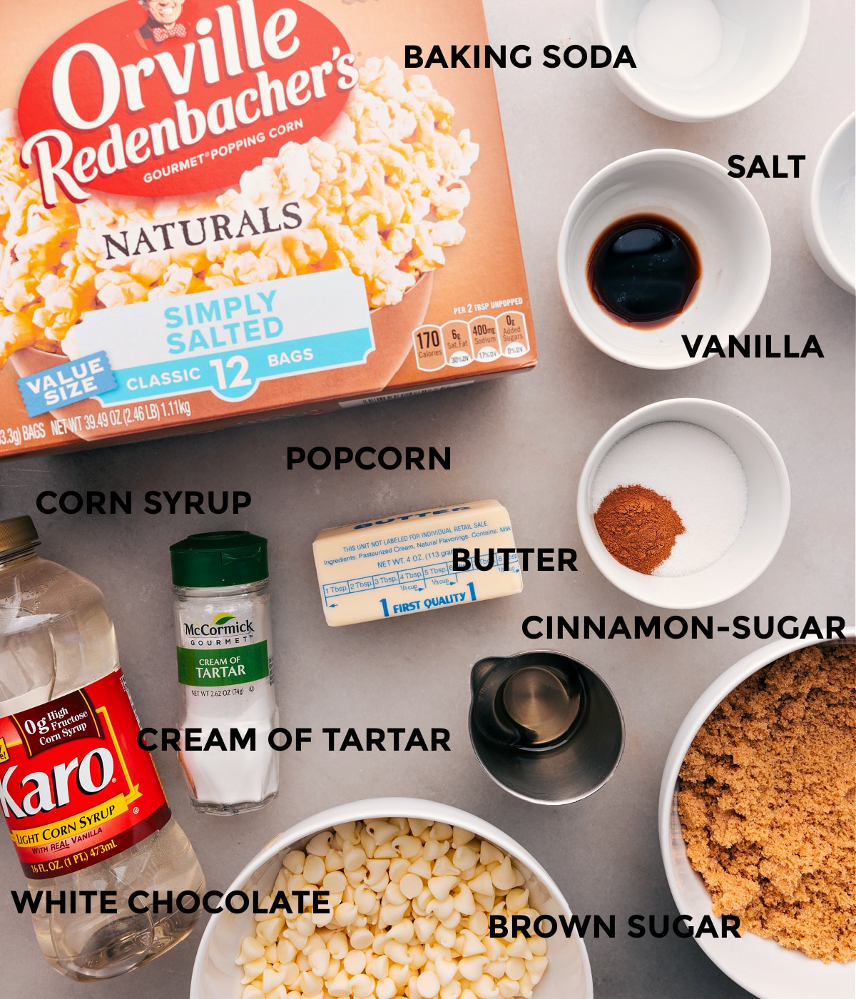 All the ingredients for this recipe are prepped and ready for easy assembly: popcorn, baking soda, salt, spices, cream of tartar, corn syrup, sugar, and chocolate.