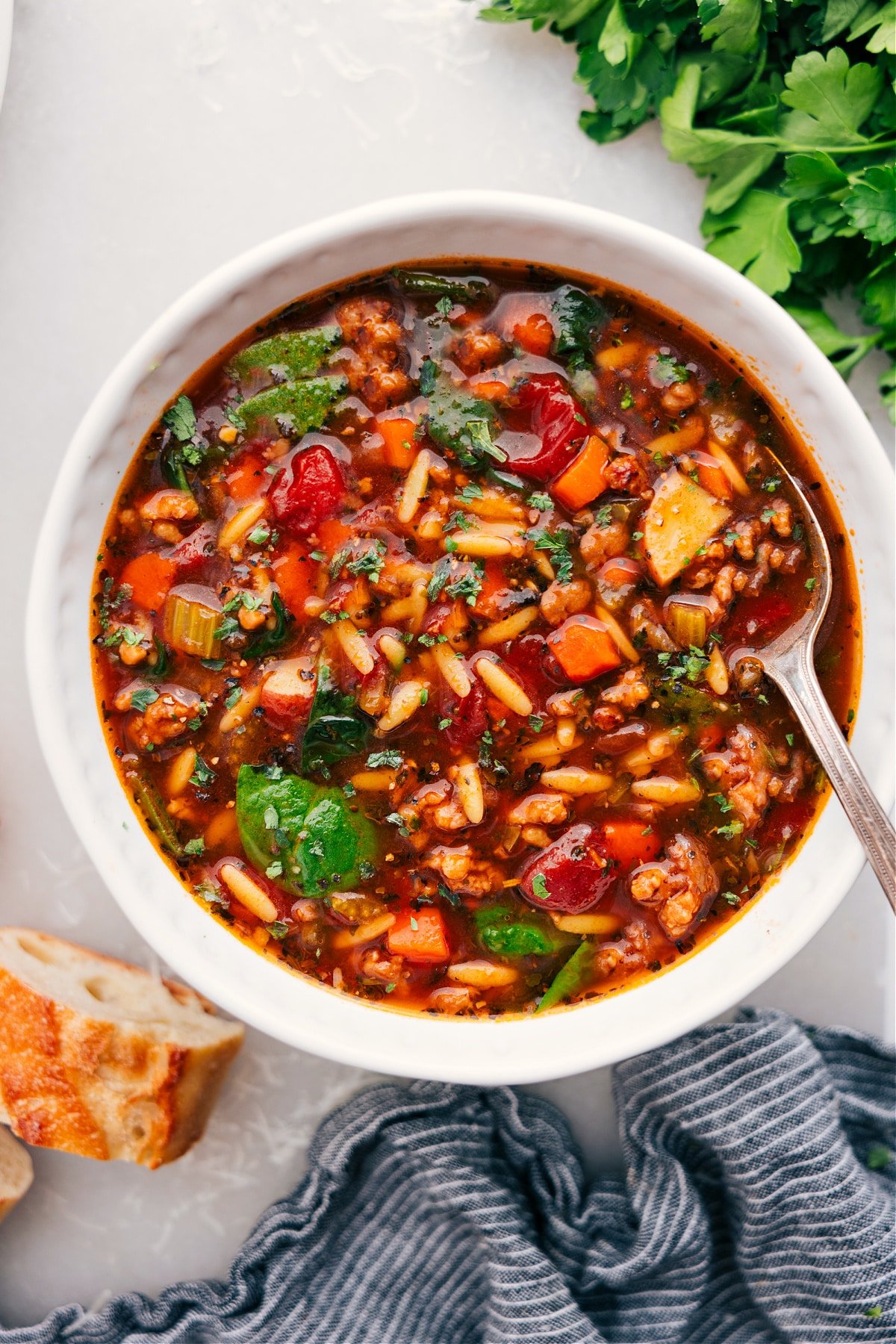 Italian Sausage Orzo Soup in a bowl with a spoon, ready for you to dig in.