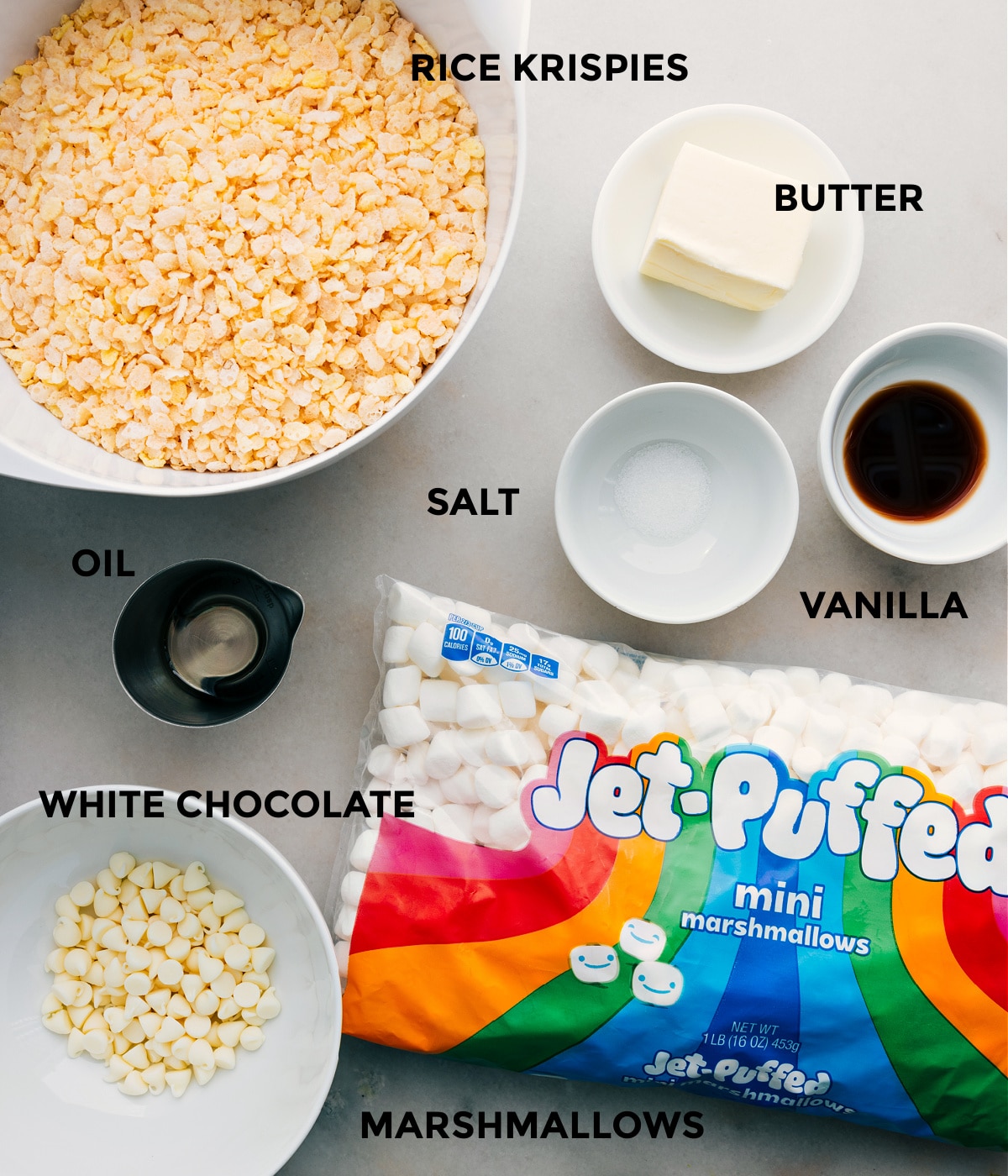 All the ingredients including cereal, butter, vanilla, salt, oil, white chocolate, and marshmallows in this recipe prepped out for easy assembly.