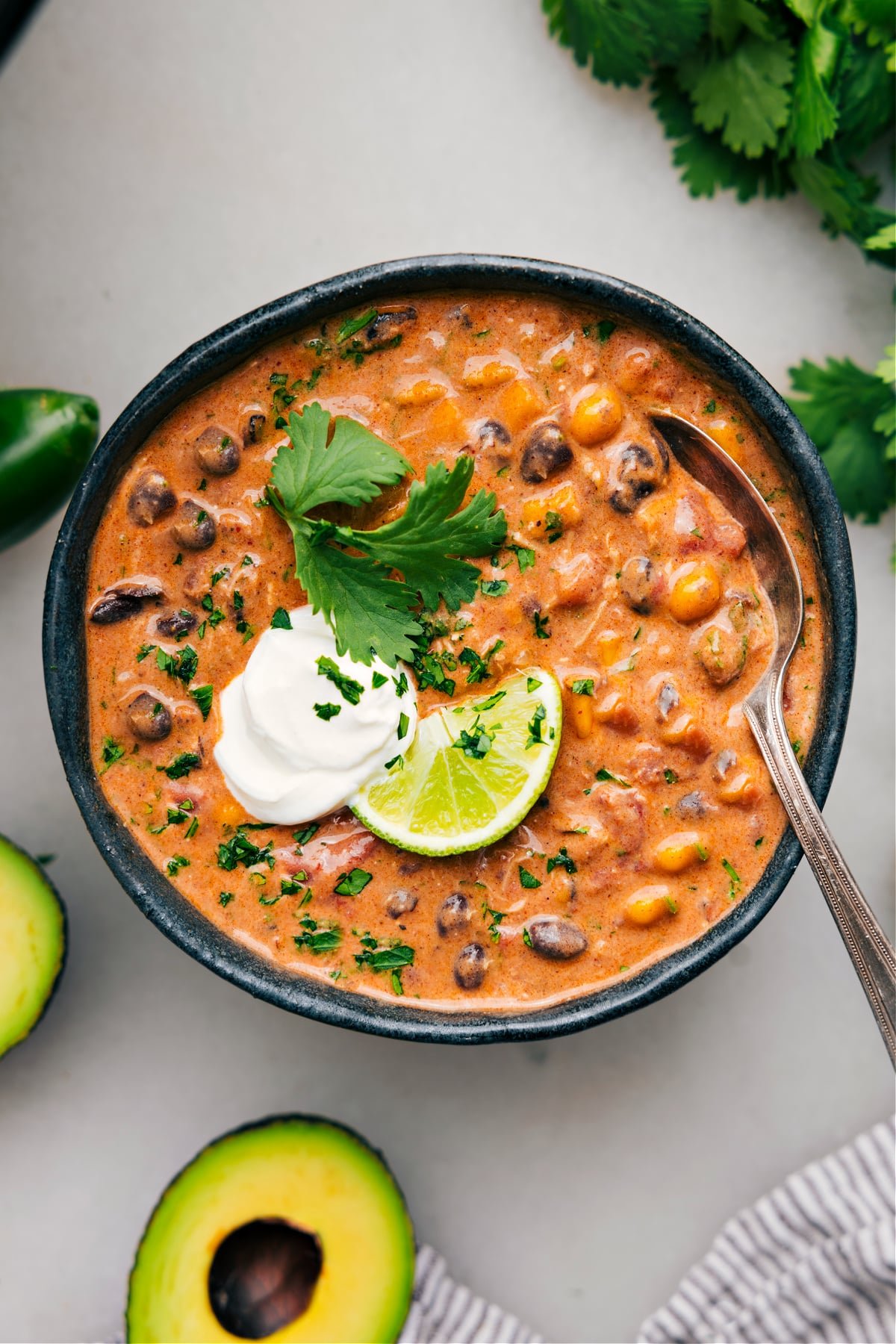 A big bowl of chicken chili topped with fresh lime, cilantro, and a dollop of sour cream.