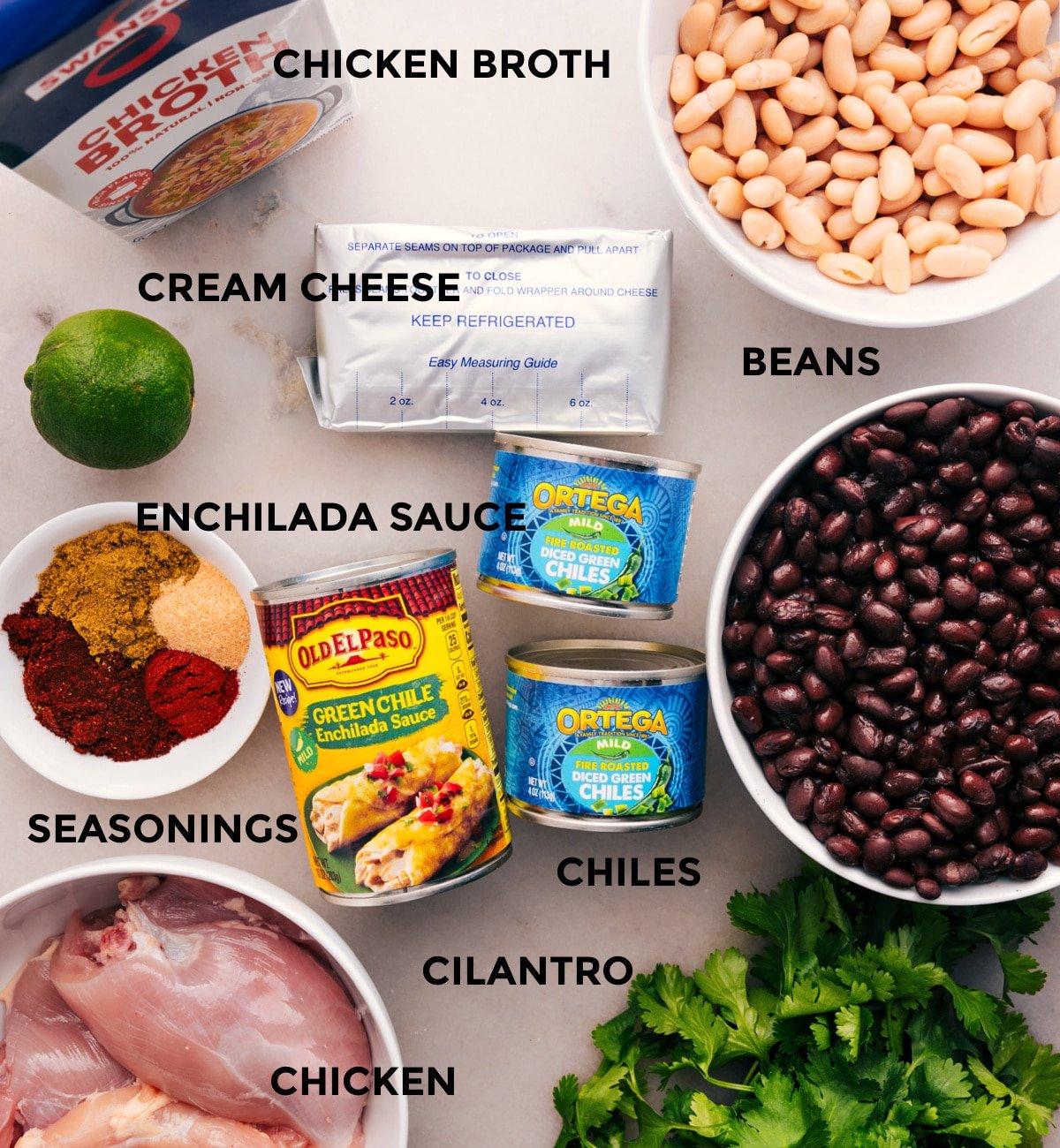 This recipe's ingredients are prepped for easy assembly: beans, meat, chiles, sauce, seasonings, cream cheese, lime, and cilantro.