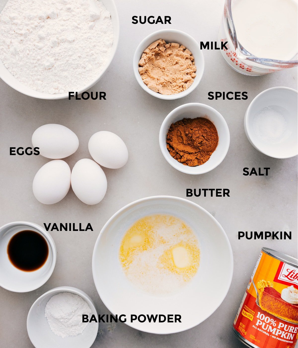 All the ingredients in this recipe are prepped for easy assembly, including sugar, milk, spices, salt, butter, eggs, flour, baking powder, vanilla, and cocoa powder.