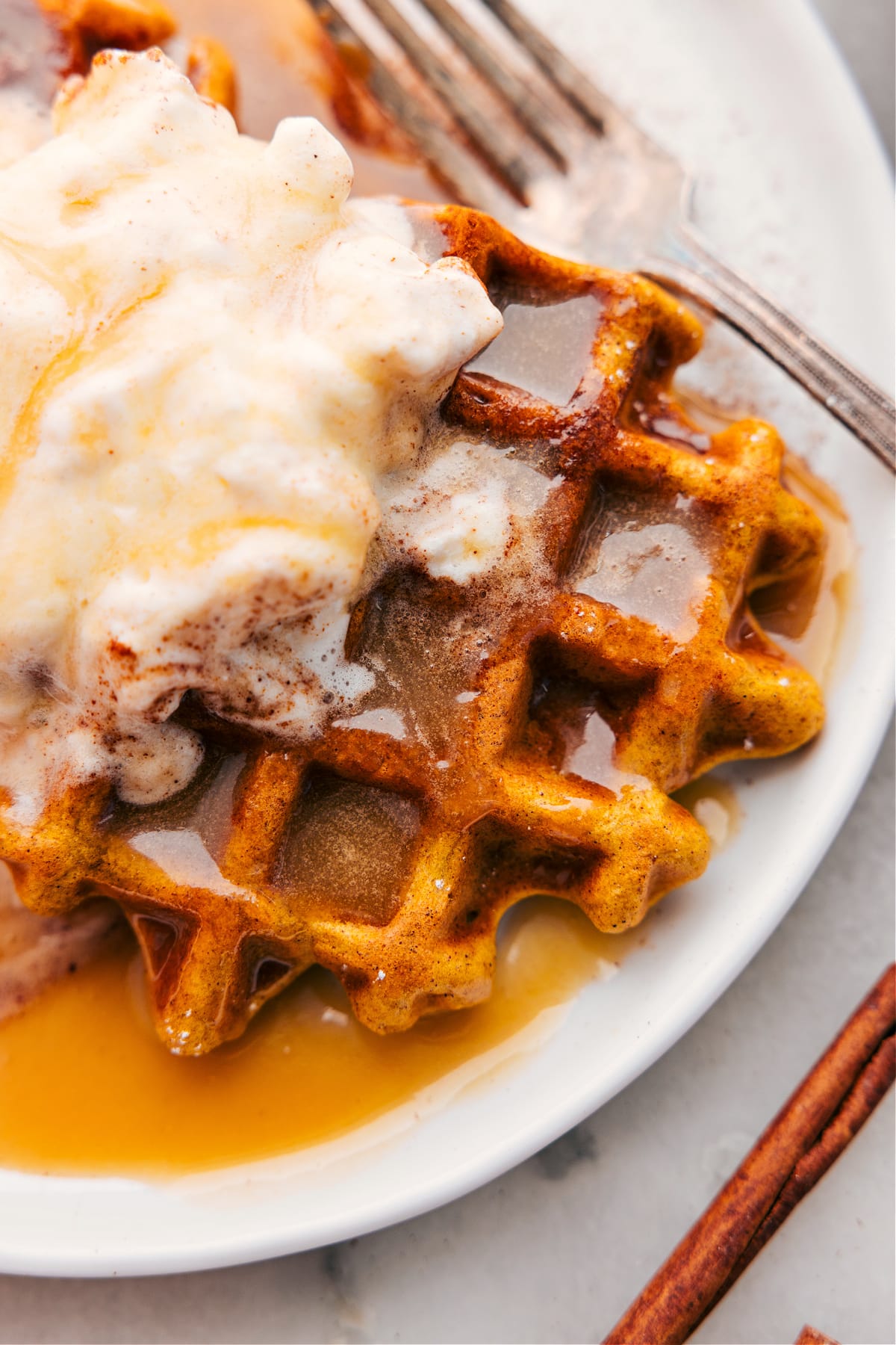 Pumpkin waffles with syrup and whipped cream ready to be enjoyed.