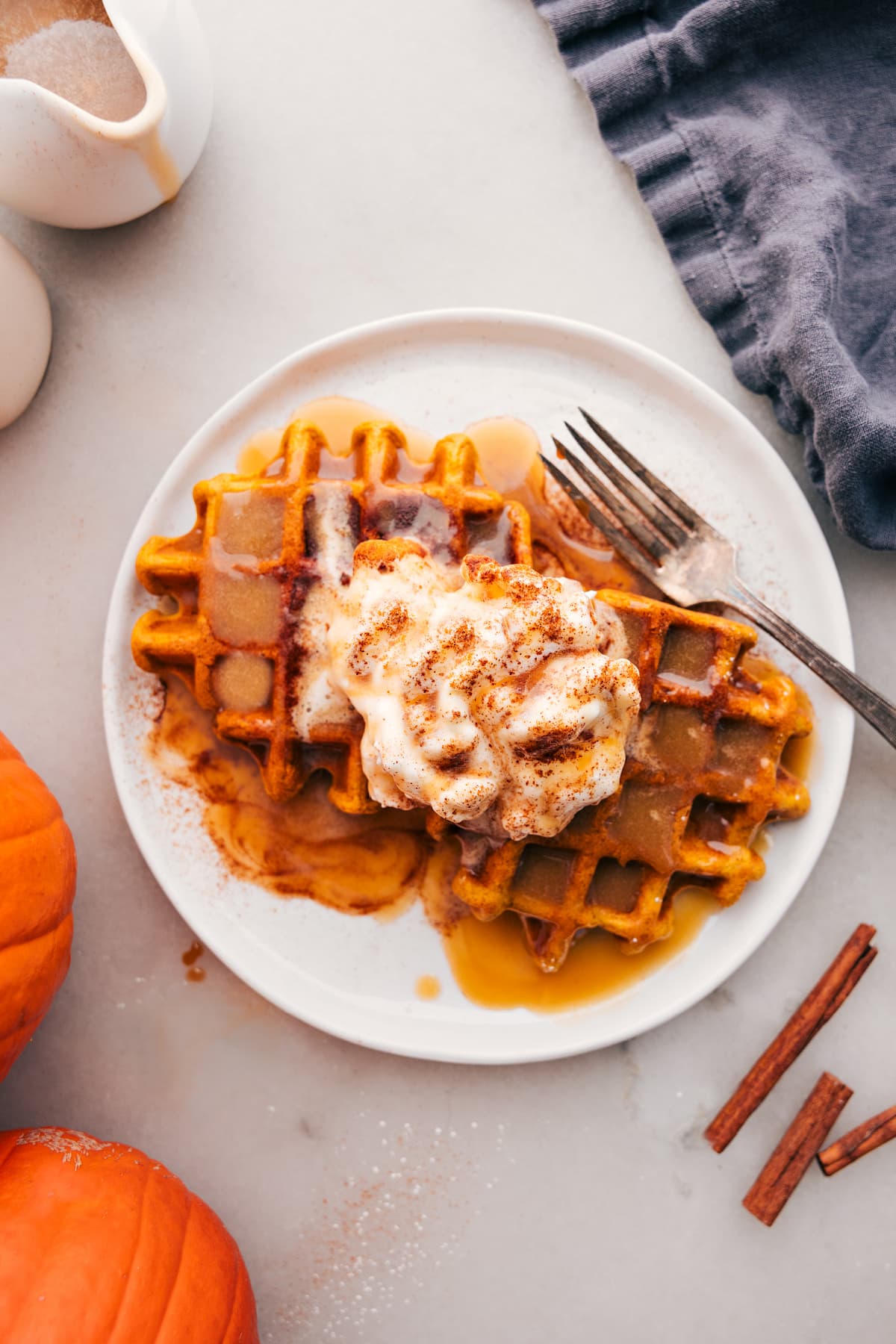 Pumpkin waffles with syrup and fresh whipped cream on top.