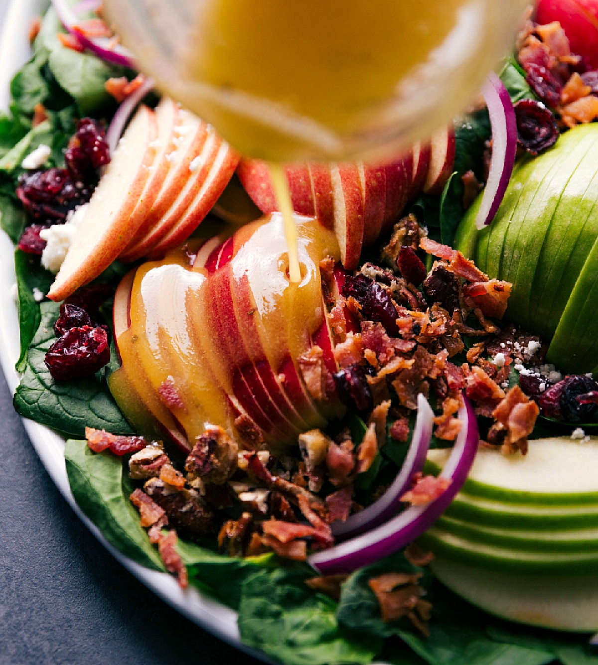 Dressing being drizzled over the recipe.