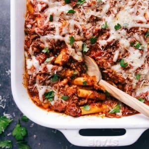 Finished baked ziti in a casserole dish, with a scoop taken out to reveal the warm, flavor-packed layers inside.