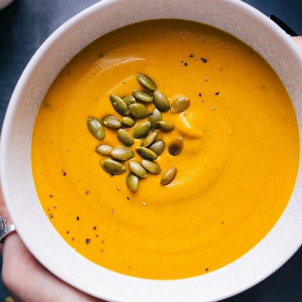 Creamy sweet potato soup in a bowl, sprinkled with crunchy pepitas, showcasing a vibrant and inviting dish ready to be enjoyed.