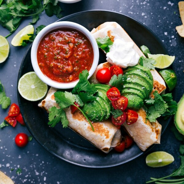 Healthy burritos garnished with avocados, tomatoes, fresh herbs, and sour cream ready to be enjoyed.