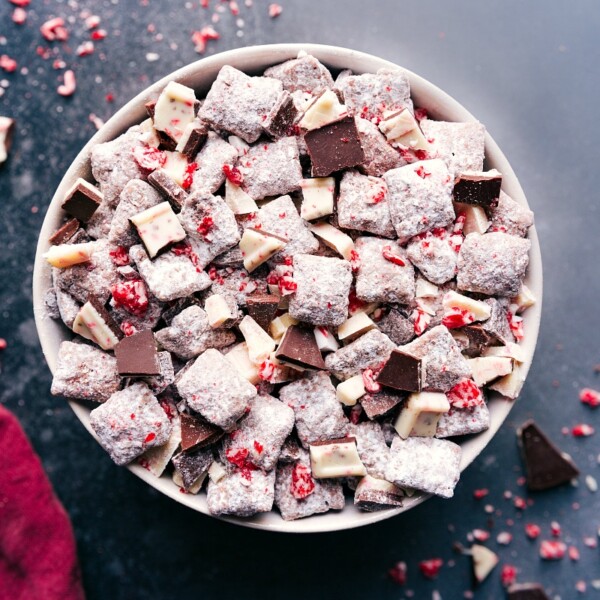 A large bowl filled with peppermint bark muddy buddies, coated in powdered sugar and crushed peppermint.