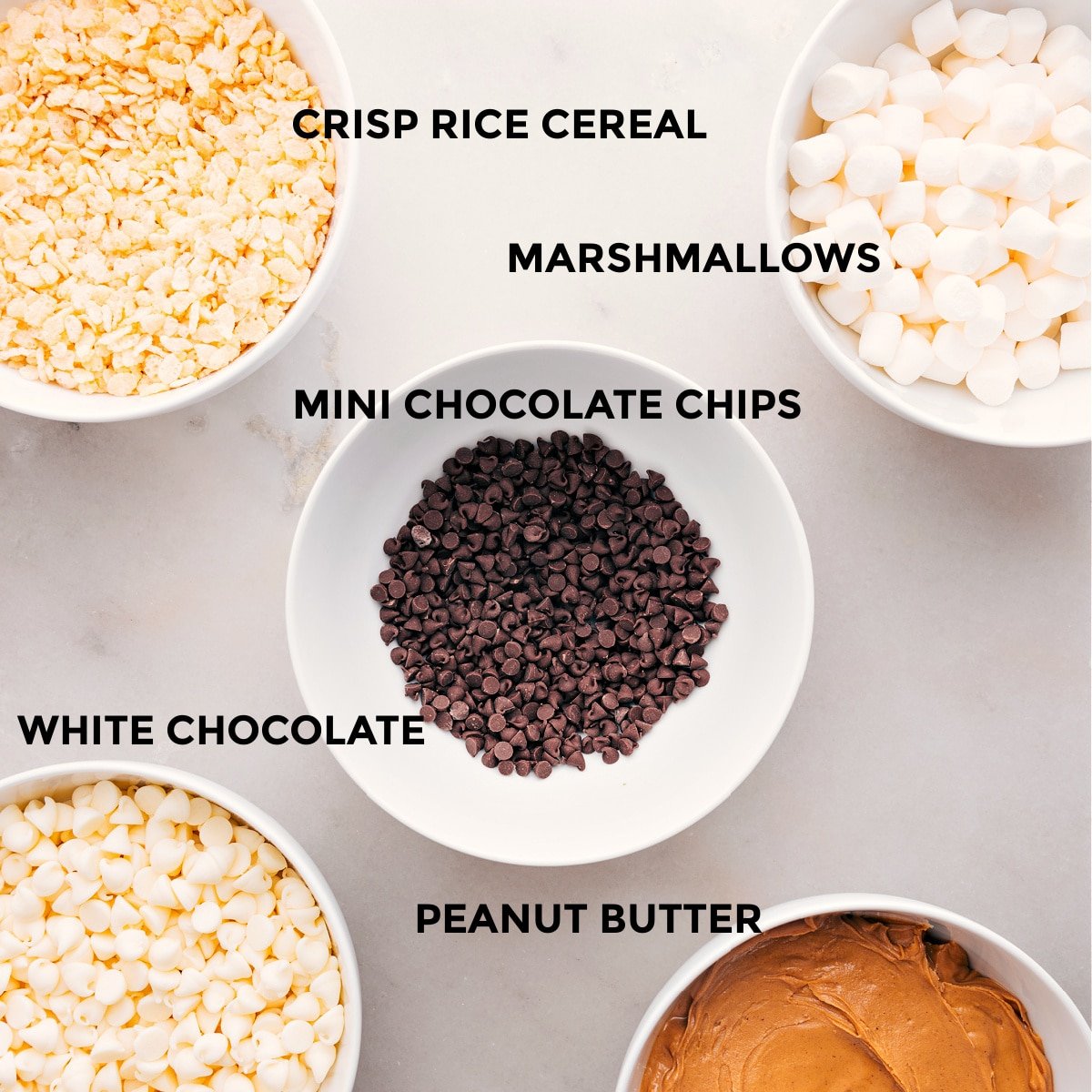 All the ingredients for this recipe are prepped and ready for easy assembly: marshmallows, chocolate chips, white chocolate, peanut butter, and Rice Krispie cereal.