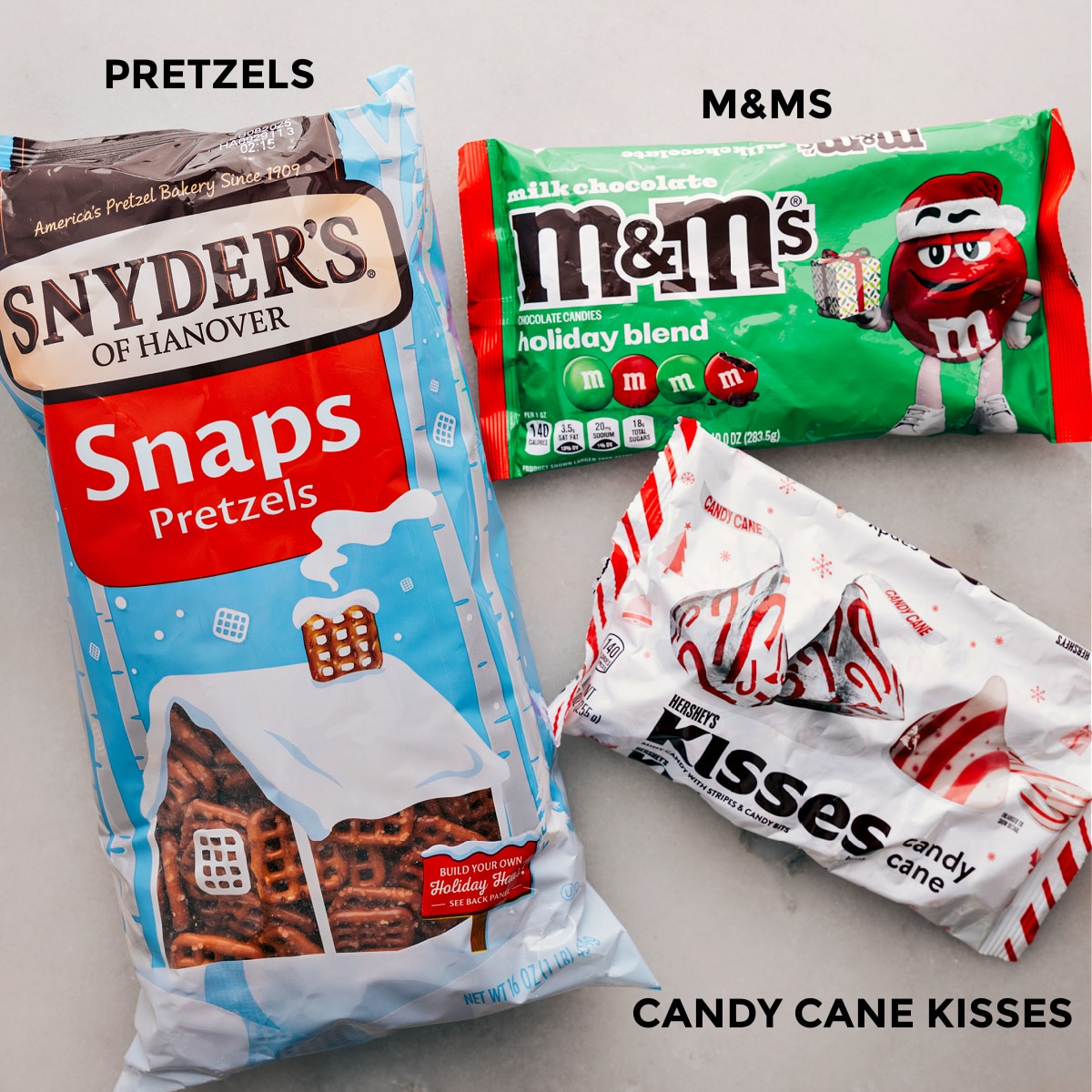 The three ingredients for this recipe—pretzels, M&Ms, and chocolate kisses—are prepped and ready for easy assembly.