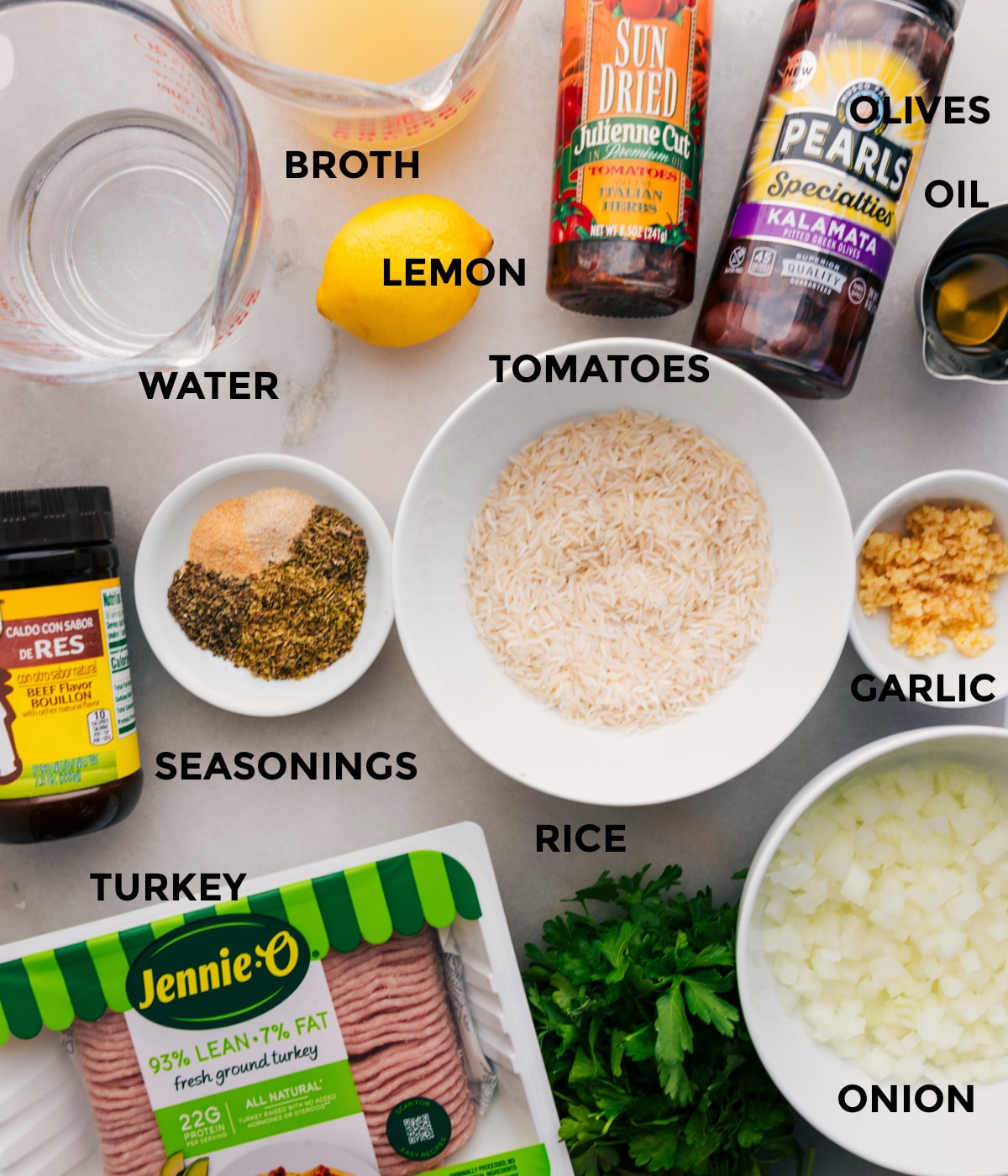 This recipe includes prepped ingredients like rice, veggies, meat, seasonings, olives, tomatoes, oil, broth, water, and lemons for easy assembly.