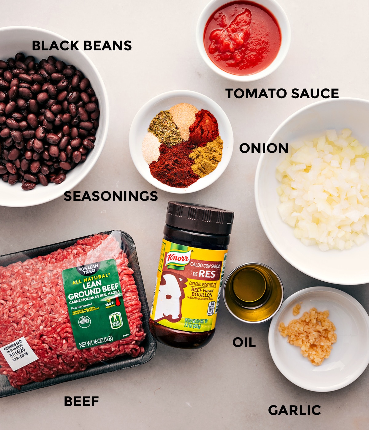 All the ingredients for this recipe are prepped and ready for easy assembly, including tomato sauce, beef, onion, black beans, seasonings, oil, and garlic.