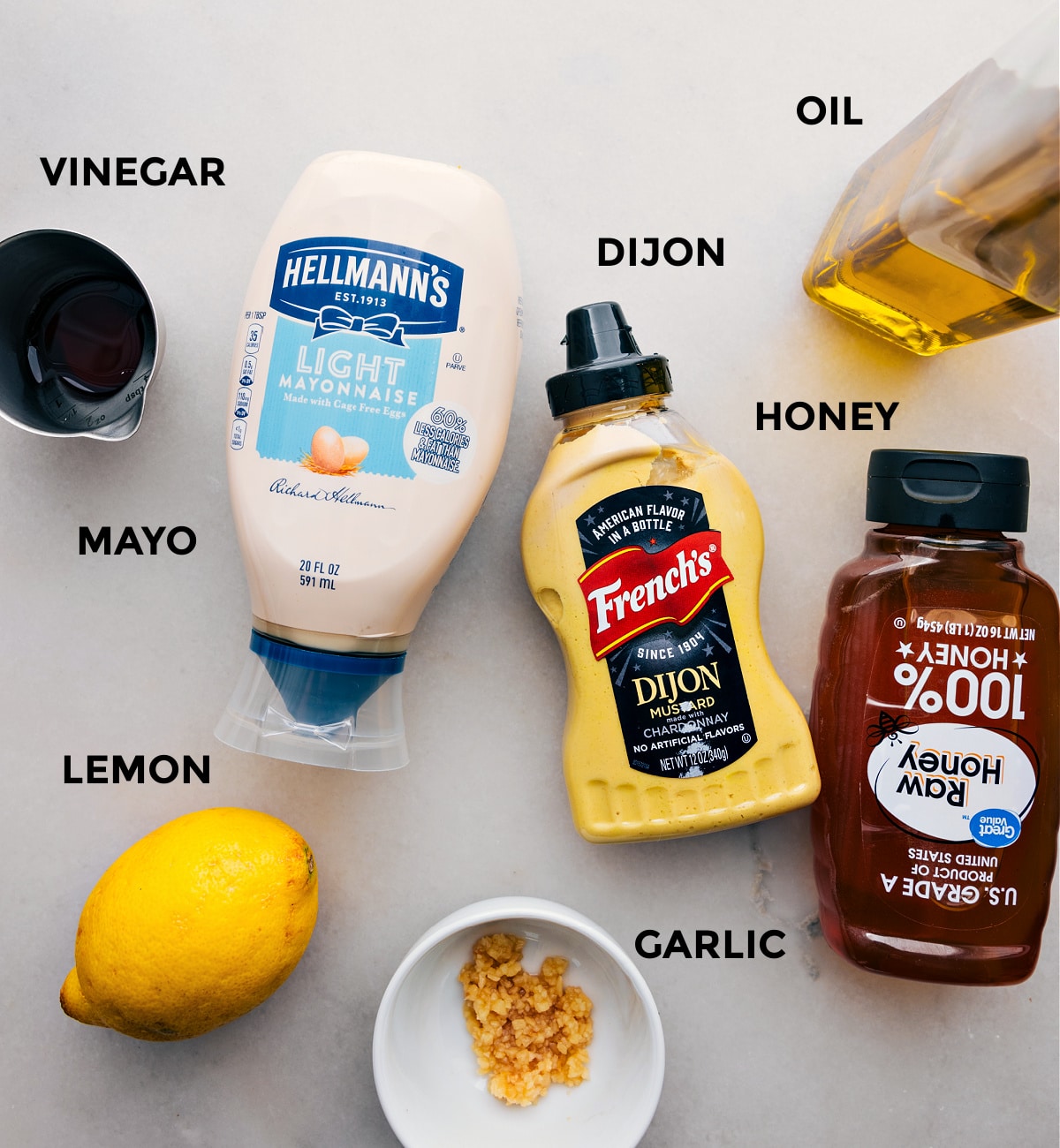 The ingredients, including mayo, vinegar, Dijon, oil, honey, lemon, and garlic, are prepped to make this dressing.