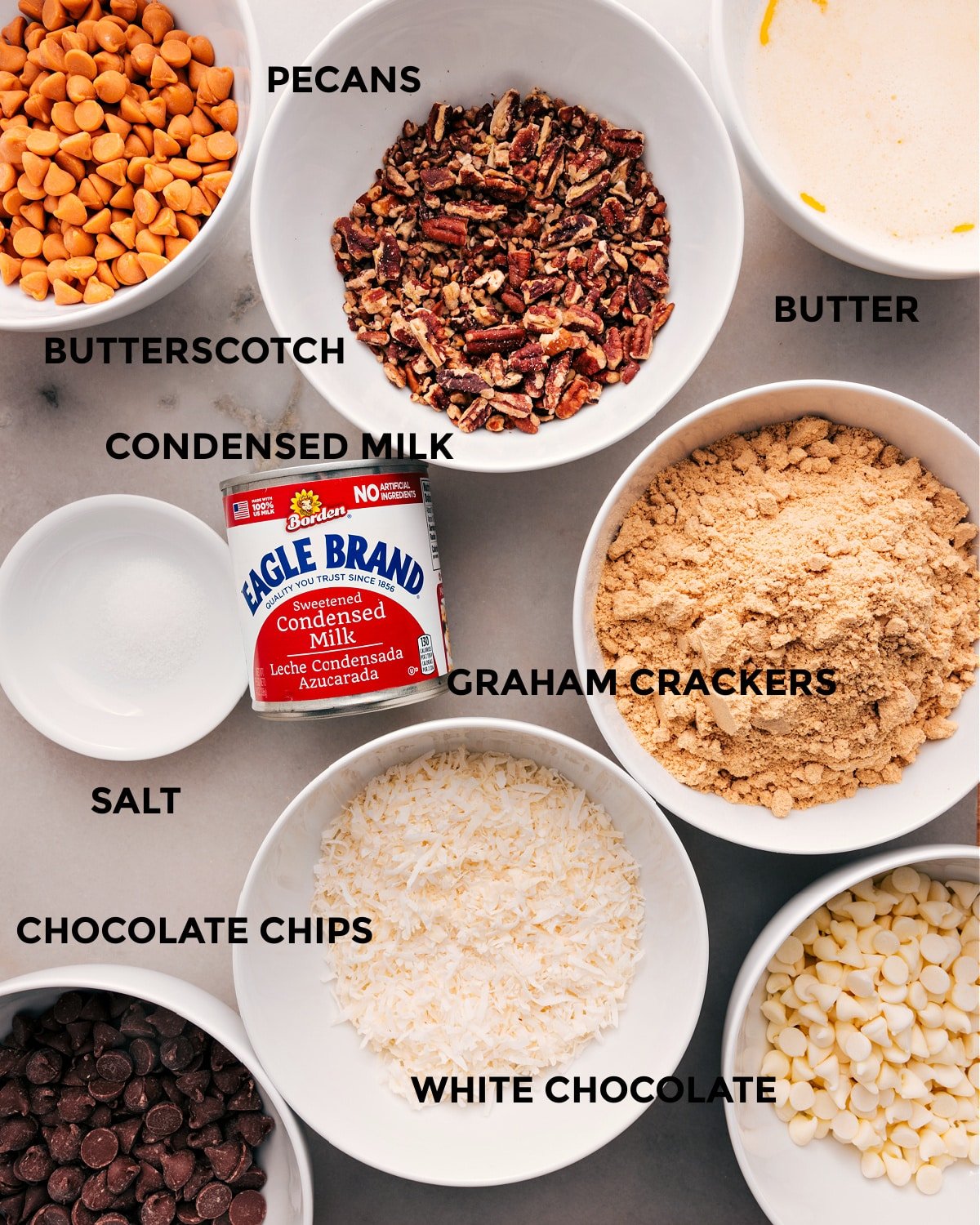 All the ingredients prepped for easy assembly—butter, butterscotch, pecans, condensed milk, graham crackers, salt, coconut, and chocolate chips.