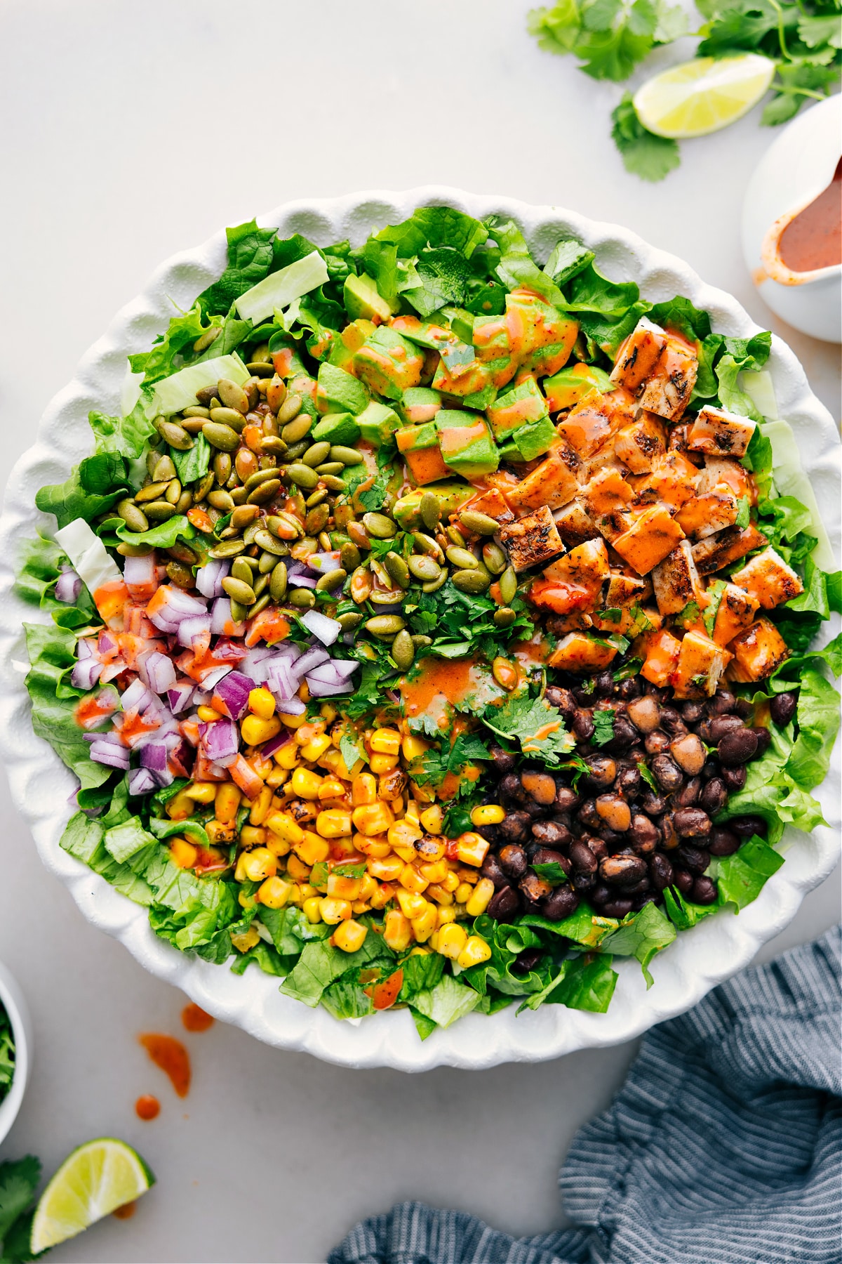 Chipotle Chicken Salad featuring rotisserie chicken, avocado, corn, black beans, red onion, pumpkin seeds, and cilantro tossed in chipotle-lime vinaigrette.