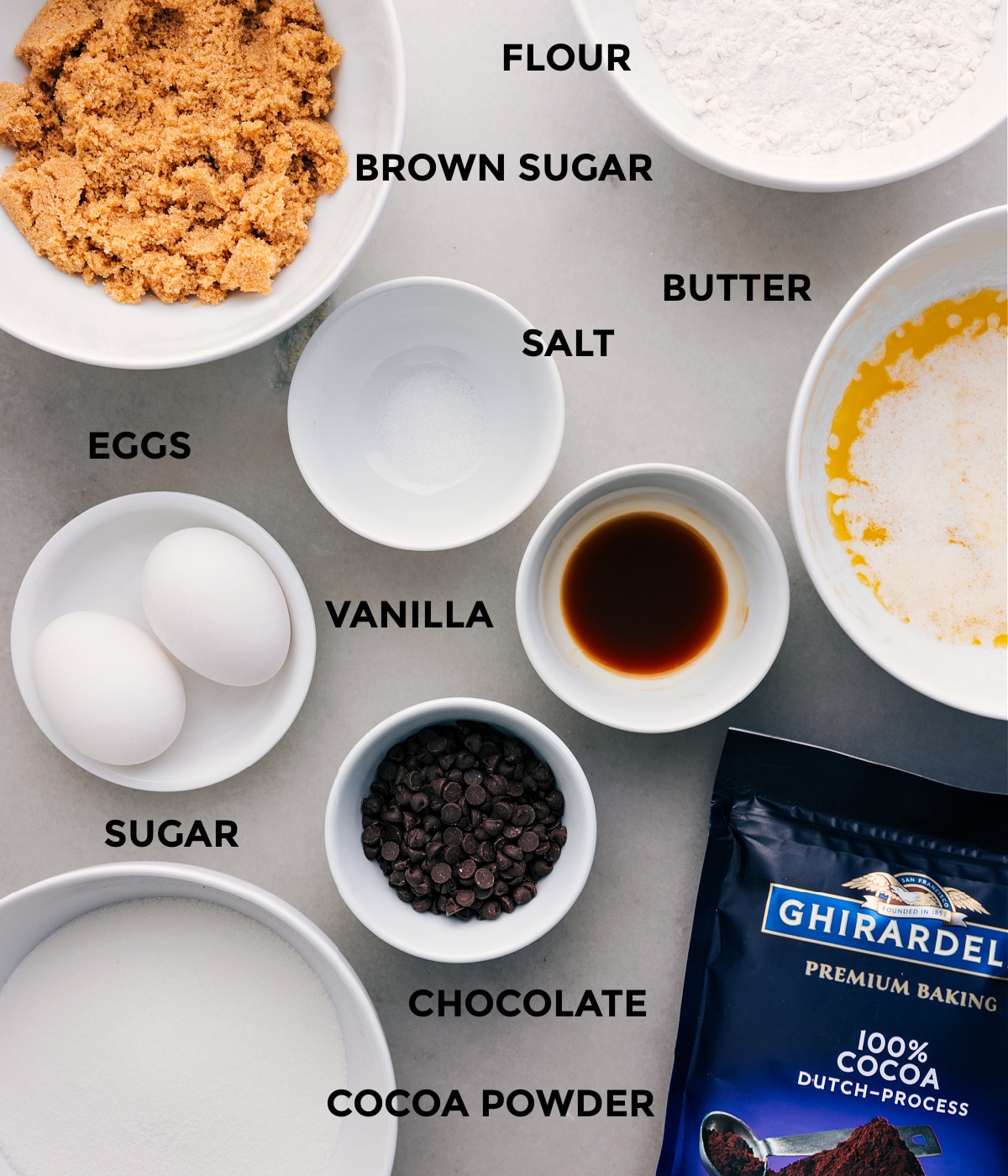 All the ingredients—butter, salt, flour, eggs, vanilla, cocoa powder, chocolate, and sugar—are prepped for easy assembly.