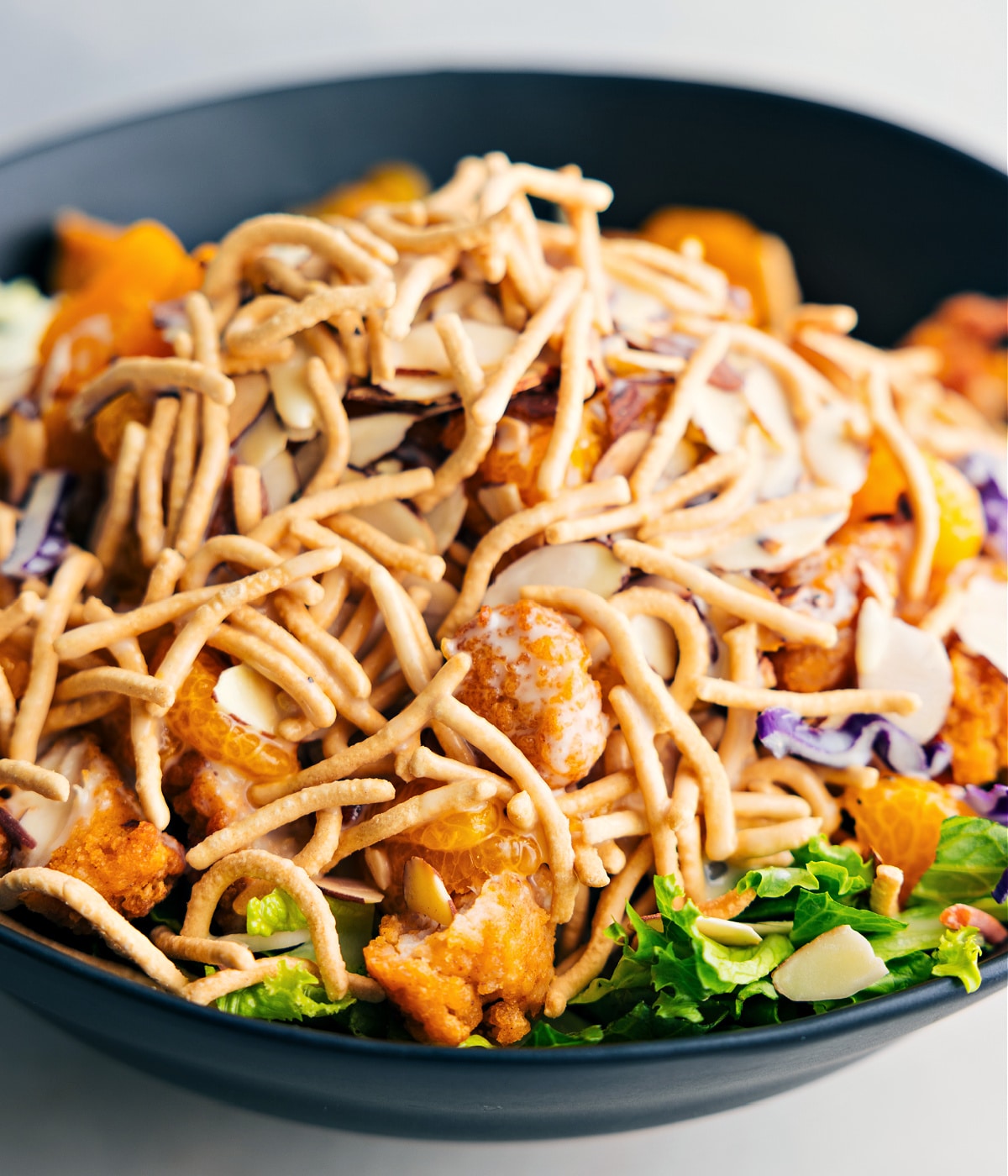 The dish tossed together in a bowl showing the crispy chow mein noodles.