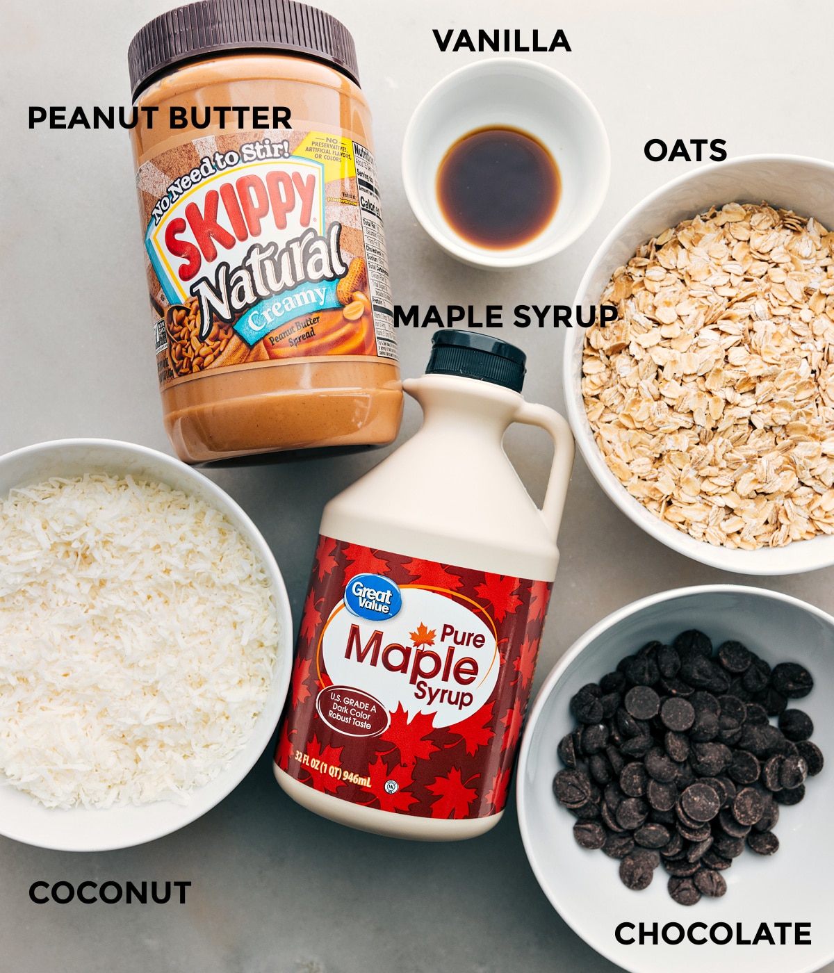 All the ingredients in this recipe, including peanut butter, vanilla, oats, maple syrup, coconut, and chocolate, are prepped for easy assembly.