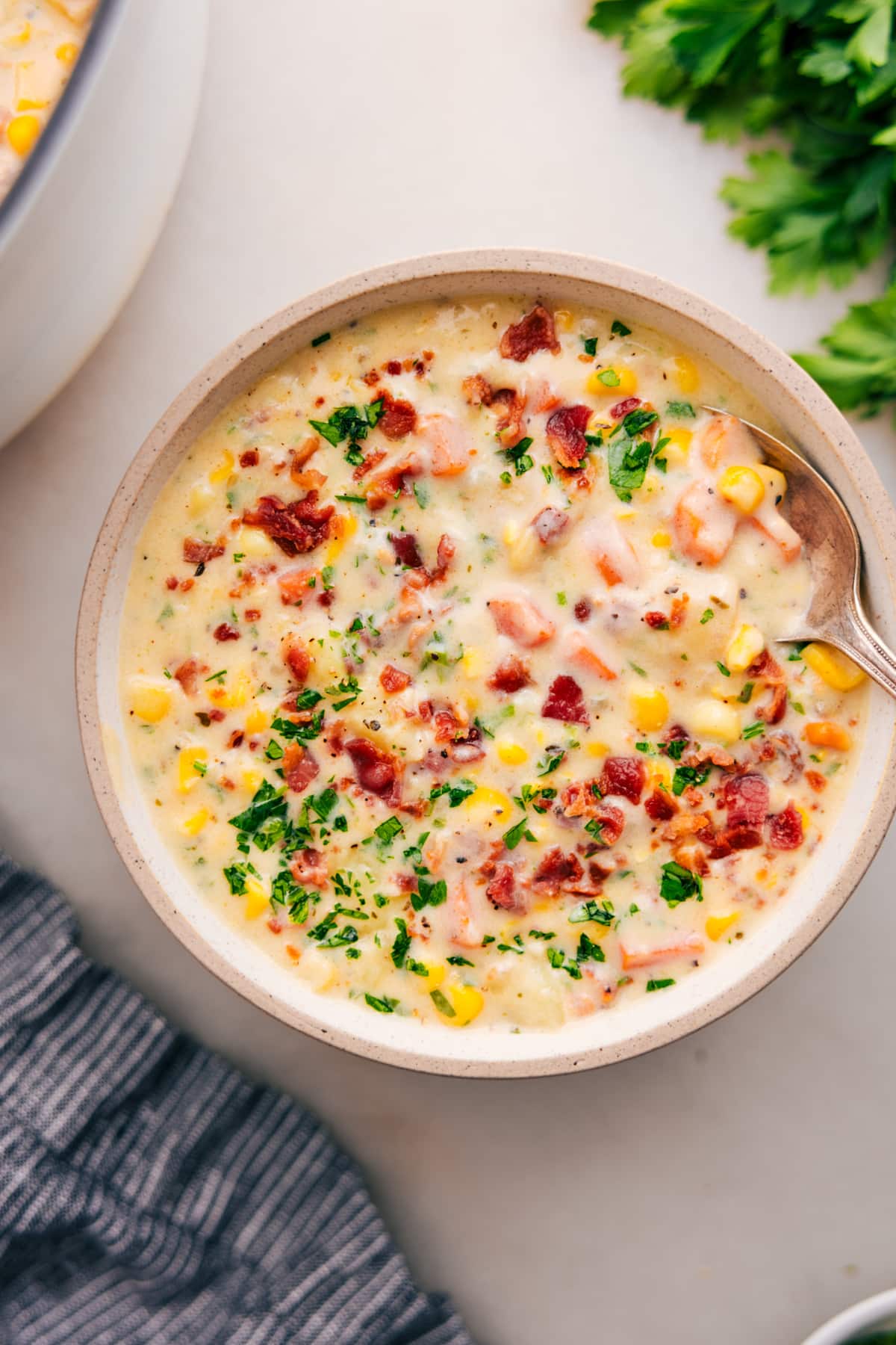 Corn chowder topped with crumbled bacon and fresh parsley in a bowl.