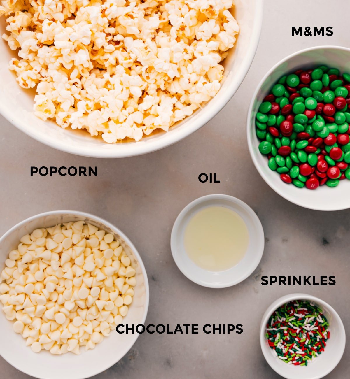 Prep all the ingredients for easy assembly: M&Ms, oil, sprinkles, popcorn, and white chocolate.