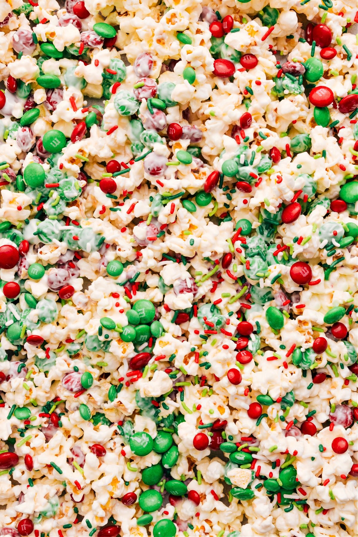 Spread Christmas Popcorn on a sheet pan and add toppings.