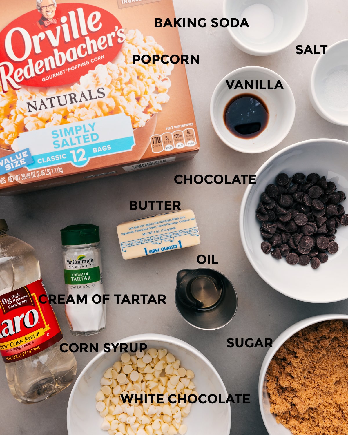 All the ingredients for this recipe prepped and ready for easy assembly: baking soda, salt, unpopped corn, vanilla, chocolate, butter, cream of tartar, corn syrup, and sugar.