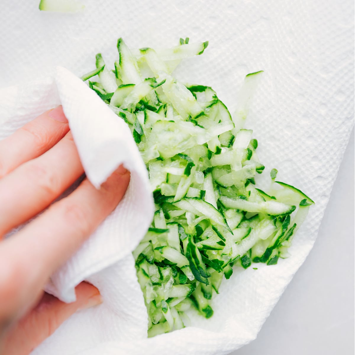 Pressing out extra liquid from the cucumber to keep the sauce thick.