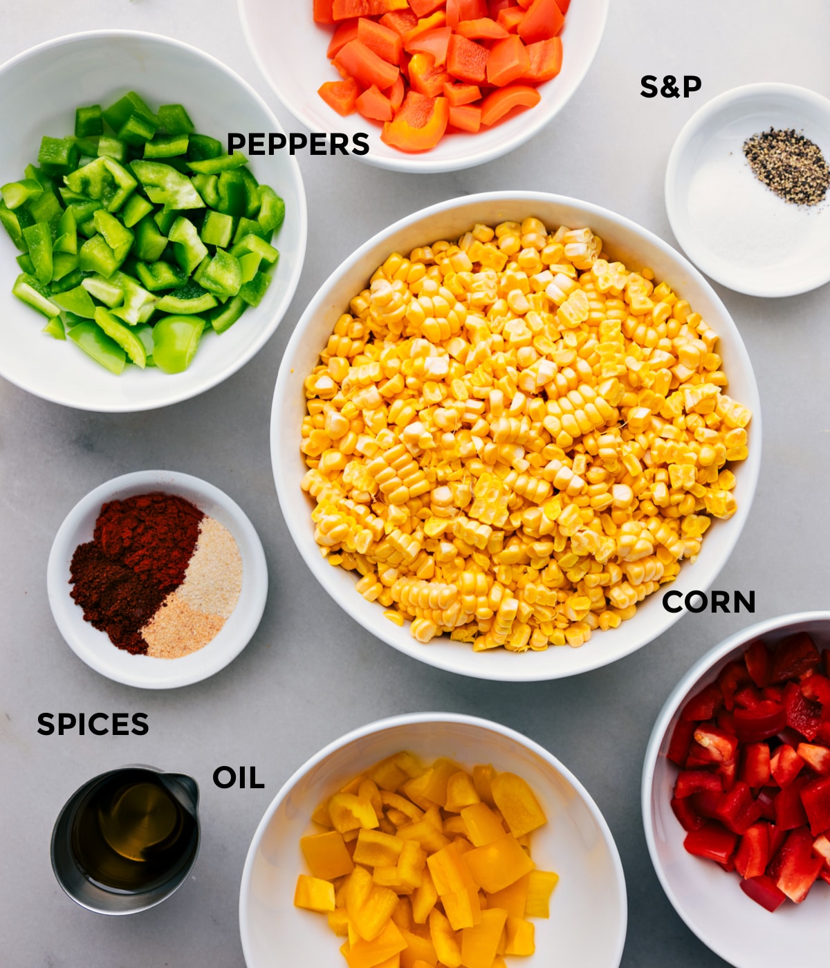 All the ingredients in this recipe including the corn, peppers, oil, spices, and seasonings prepped out for easy assembly.