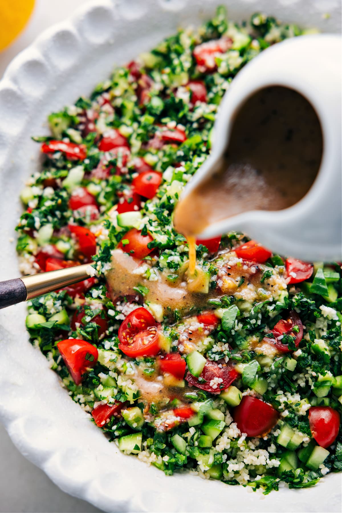 Tabouli tossed in a bowl with dressing drizzled on top.