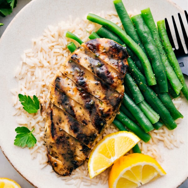 Italian Chicken Marinade recipe on a plate over a bed of rice with green beans.