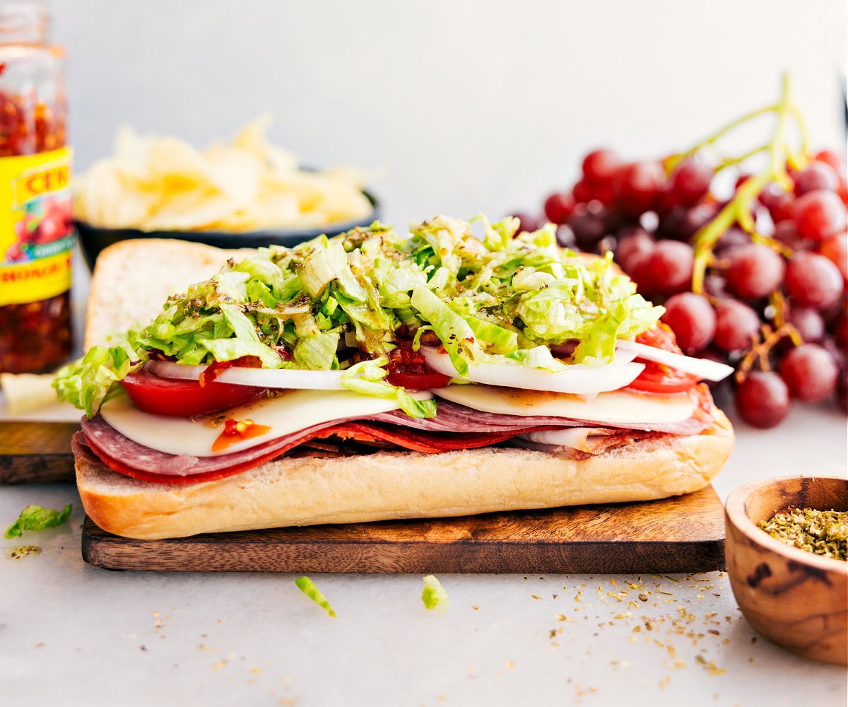 The meat and veggies being layered onto the bread for these Italian hoagie sandwiches.