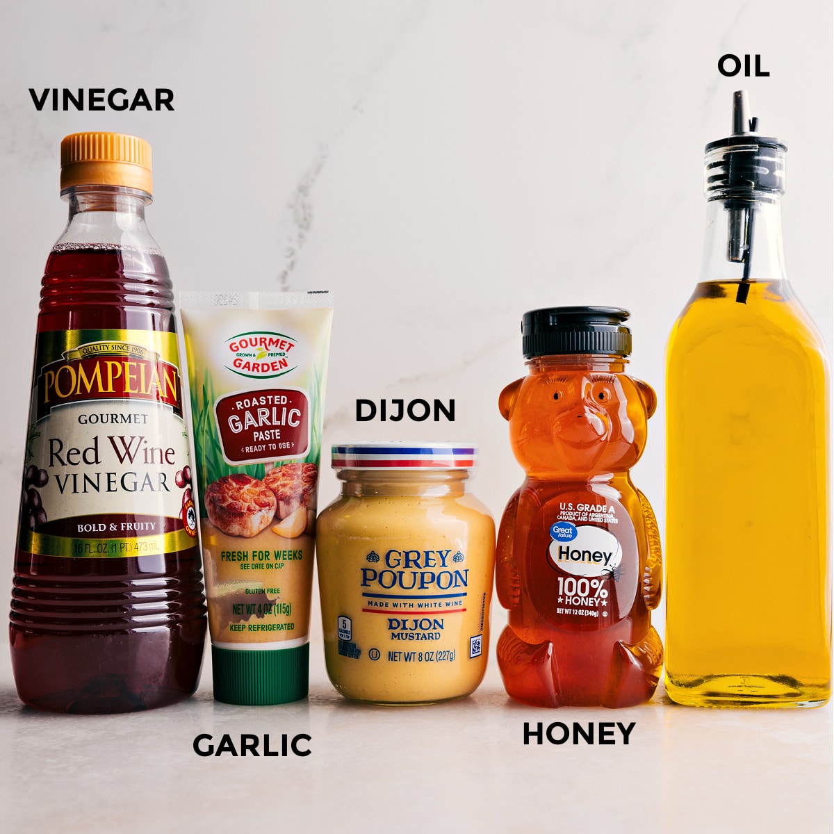 All the ingredients for the quick and simple dressing used in this everyday salad recipe prepped out including honey, oil, dijon mustard, garlic, and red wine vinegar.