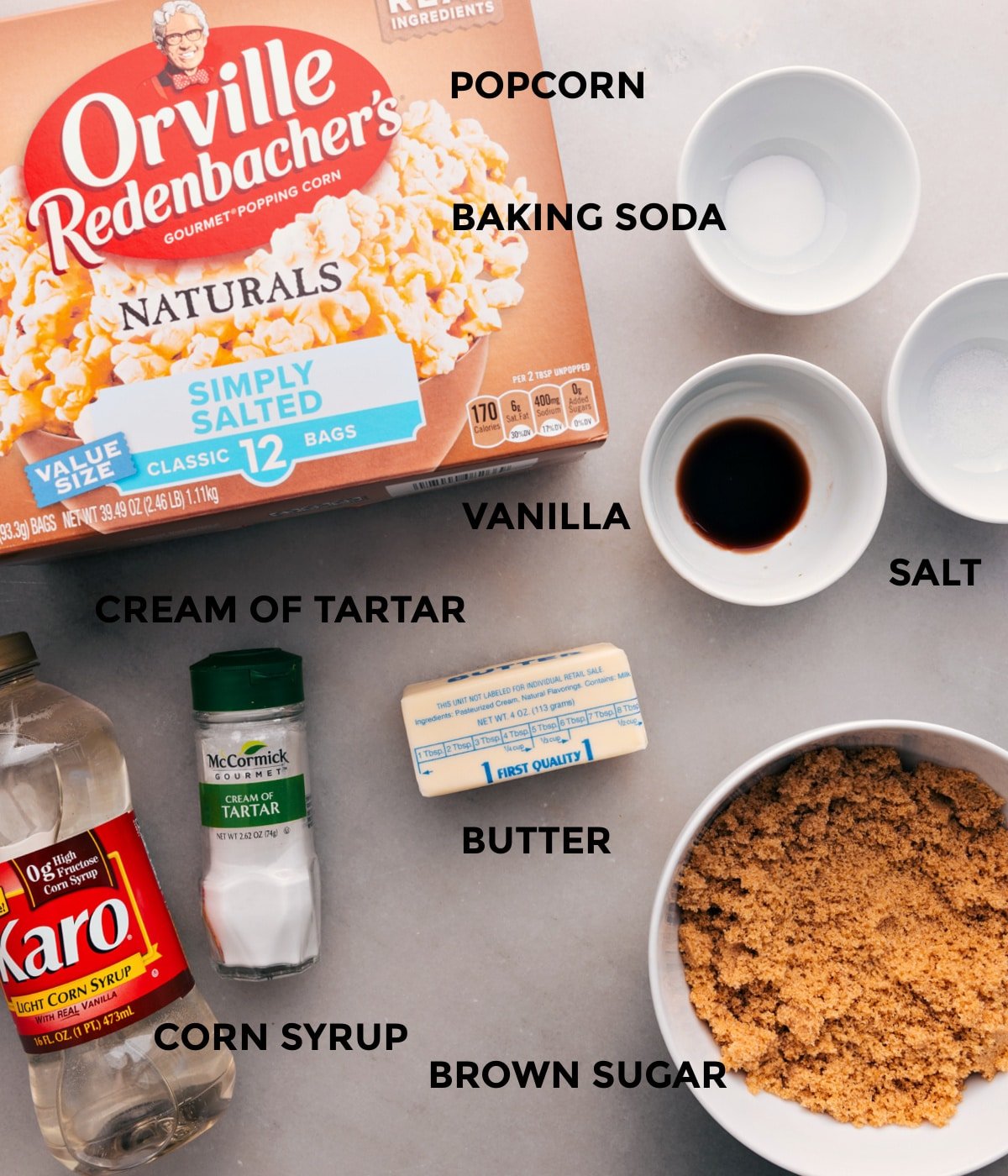 All the ingredients for this recipe are prepped for easy assembly: baking soda, salt, vanilla, butter, sugar, corn syrup, cream of tartar, and popcorn.