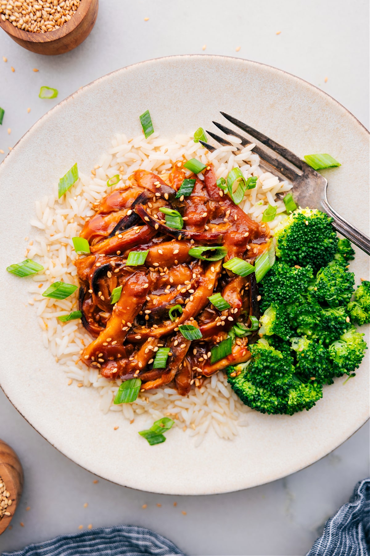 Honey Garlic Chicken Thighs served on a bed of rice, accompanied by broccoli on the side and topped with fresh green onions.