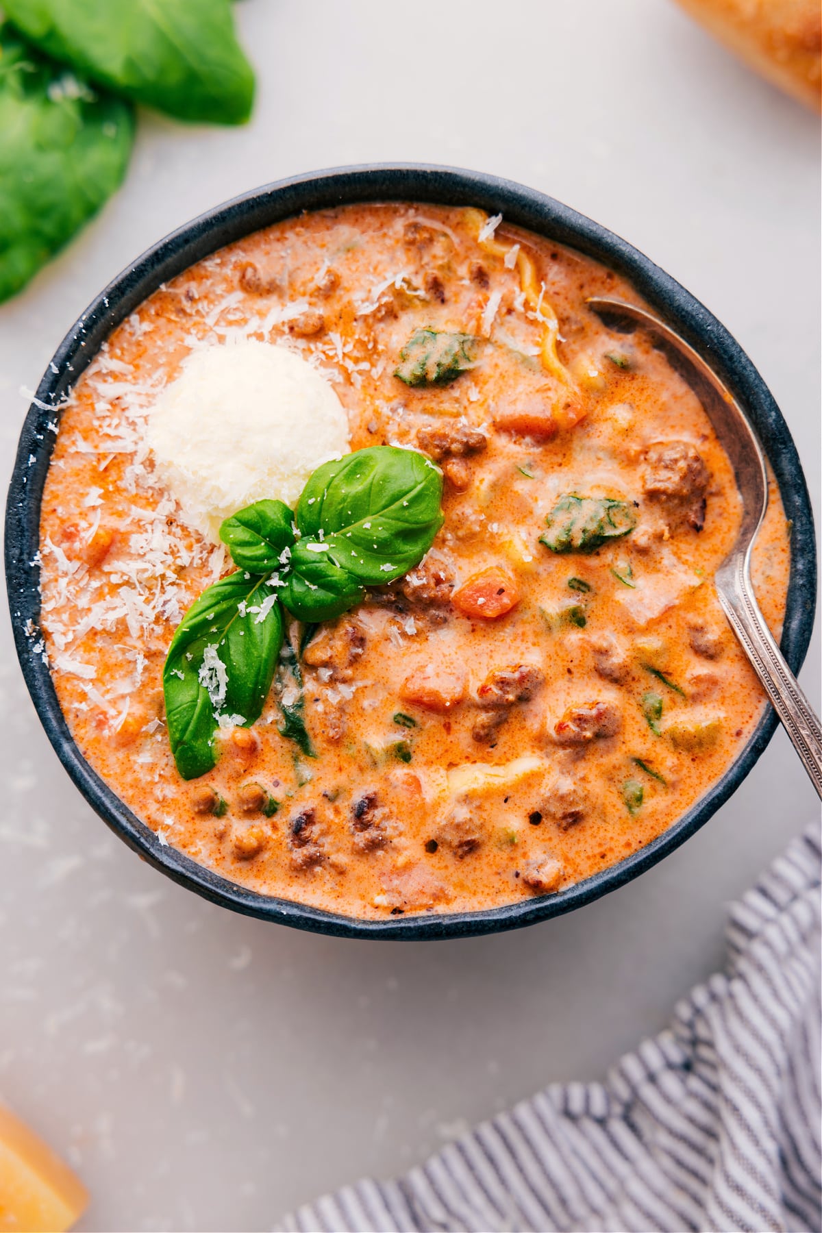 Lasagna soup served in a bowl, topped with fresh basil and freshly grated Parmesan cheese.