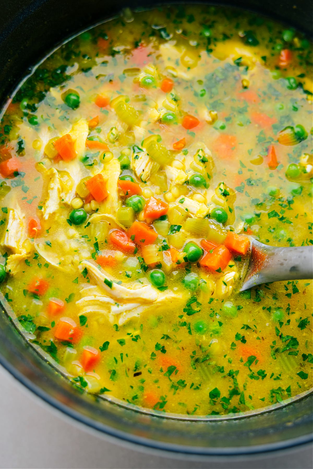 The best couscous soup recipe in the pot, with a big ladle scooping it out.