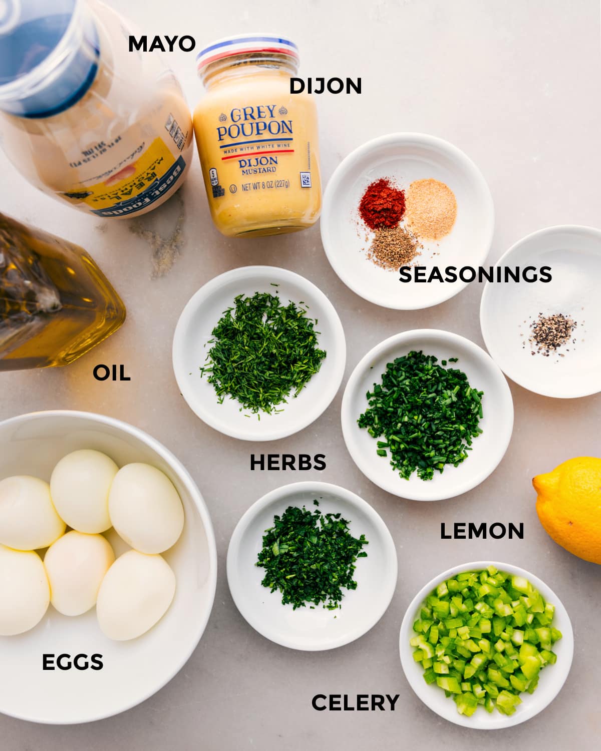 All the ingredients prepped for easy assembly, including mayo, dijon, seasonings, herbs, oil, eggs, lemon, and celery.