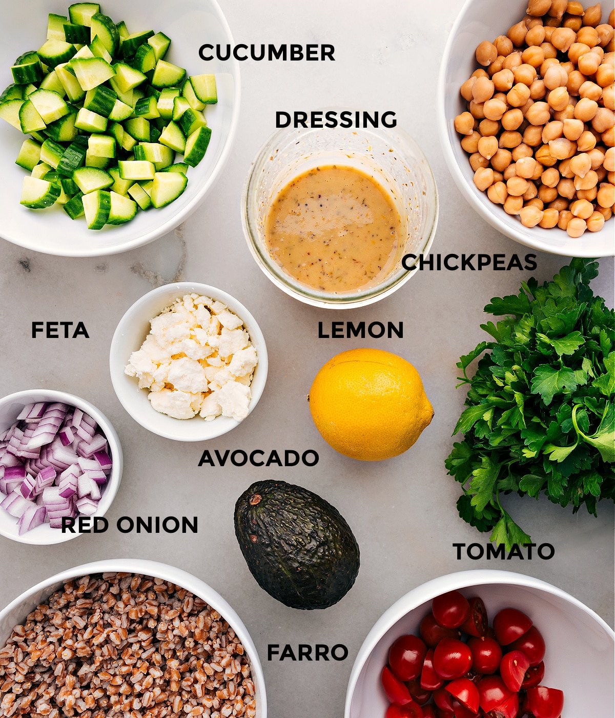 This recipe includes prepped ingredients like dressing, chickpeas, veggies, feta, lemon, farro, and parsley for easy assembly.