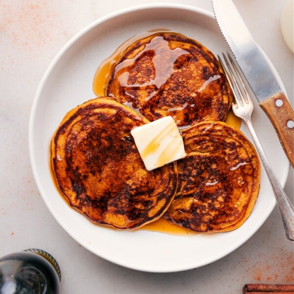 Plate of Three Pumpkin Pancakes Drizzled with Maple Syrup.