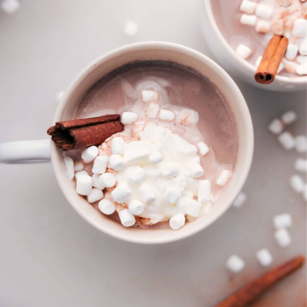 Steaming Mexican hot chocolate crowned with fluffy whipped cream, marshmallows, and a cinnamon stick for the final touch.