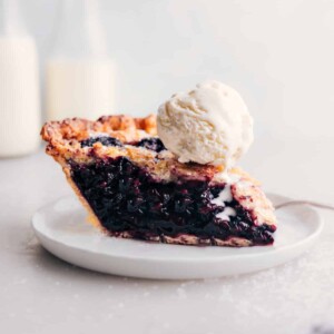 Slice of berry pie with ice cream on top.