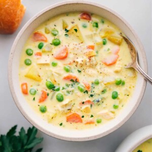 A bowl filled with the finished hearty curry chicken chowder, topped with fresh herbs, and served alongside bread for a delicious and satisfying meal.