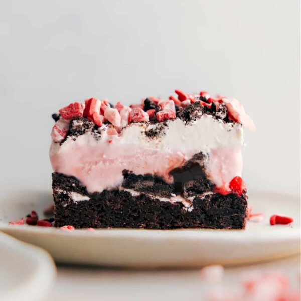 A slice of peppermint brownie ice cream bar, displaying its stunning layers with a rich brownie base, a thick layer of ice cream, and a topping of crushed peppermint, exemplifying a perfect blend of textures and flavors.