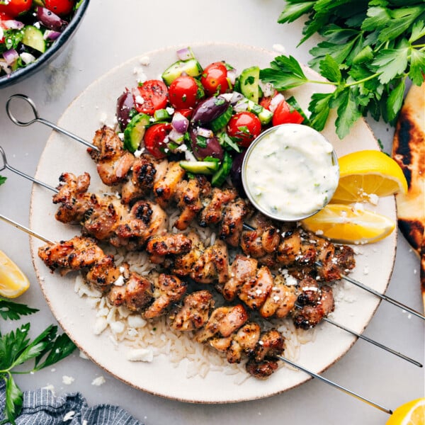 Greek Chicken Bowls on a plate with an easy greek salad, tzatziki dressing, all over rice.