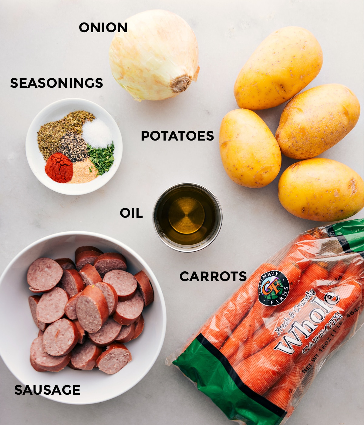 All the ingredients in this recipe including sausage, seasonings, onion, potatoes, and carrots being prepped for easy assembly.