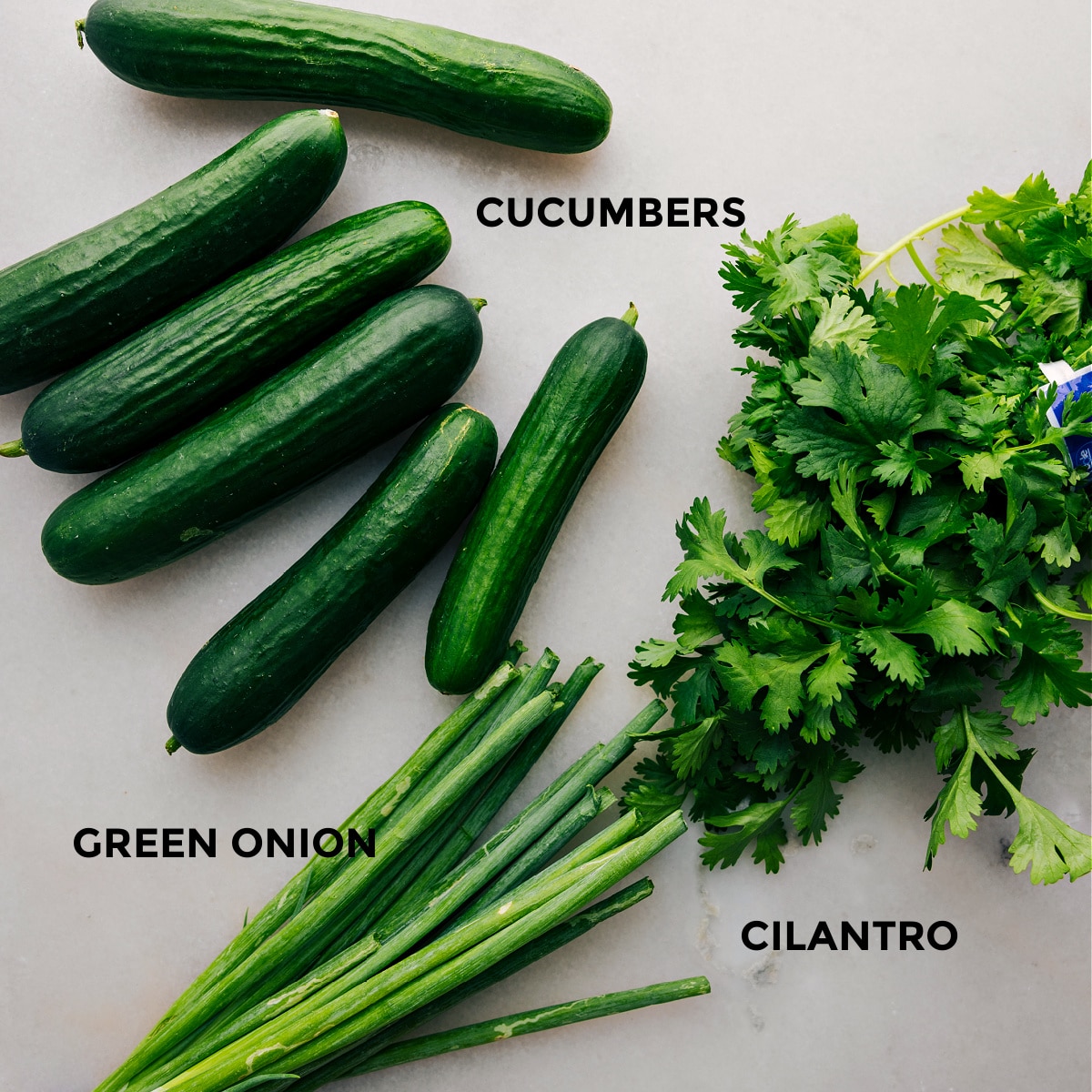 The 3 main ingredients, cucumbers, green onions, and cilantro set out to assemble this delicious cucumber salad.