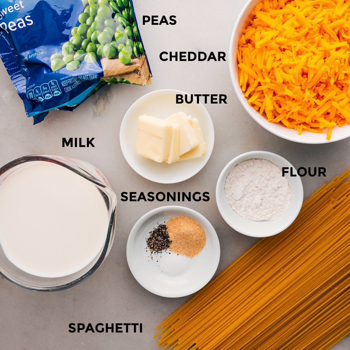 This recipe's ingredients are prepped for easy assembly: pasta, flour, cheese, butter, peas, and milk.